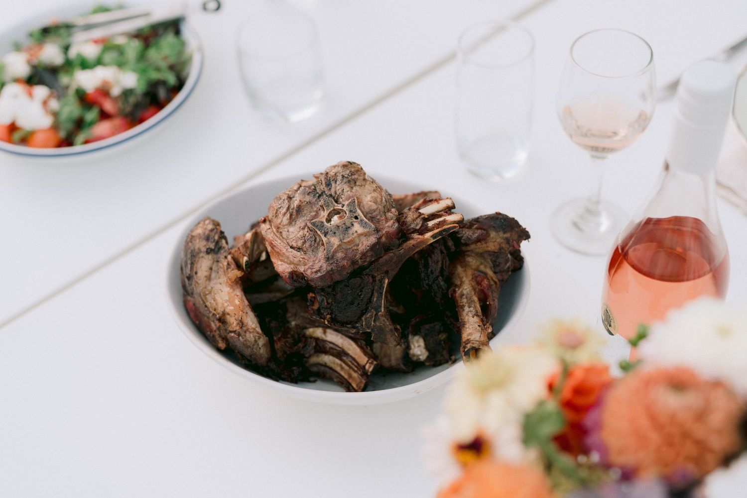 Elegant wedding reception table settings with colorful salads and wine glasses.