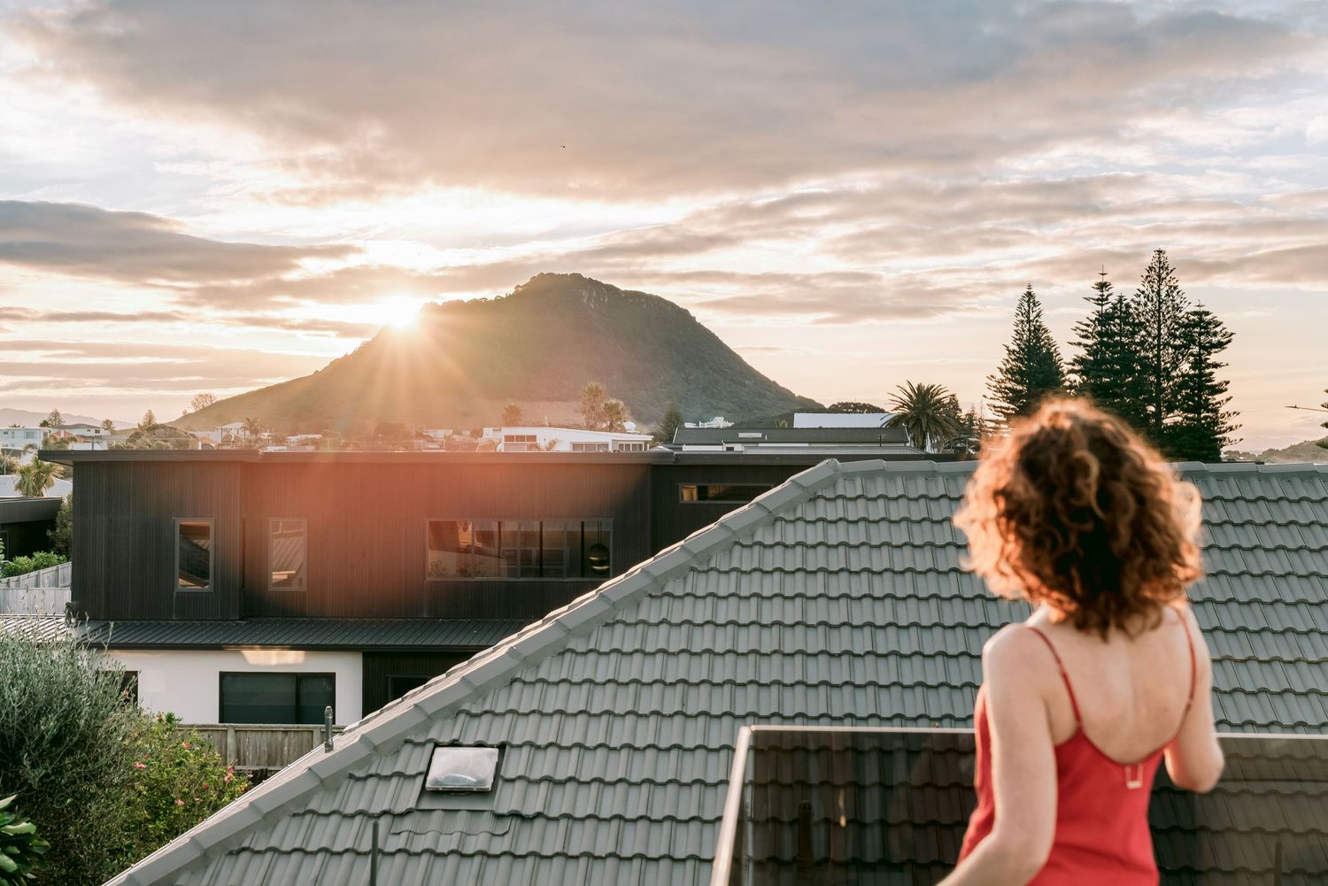 Scenic mountain sunset view from a residential rooftop with dramatic cloud formations.