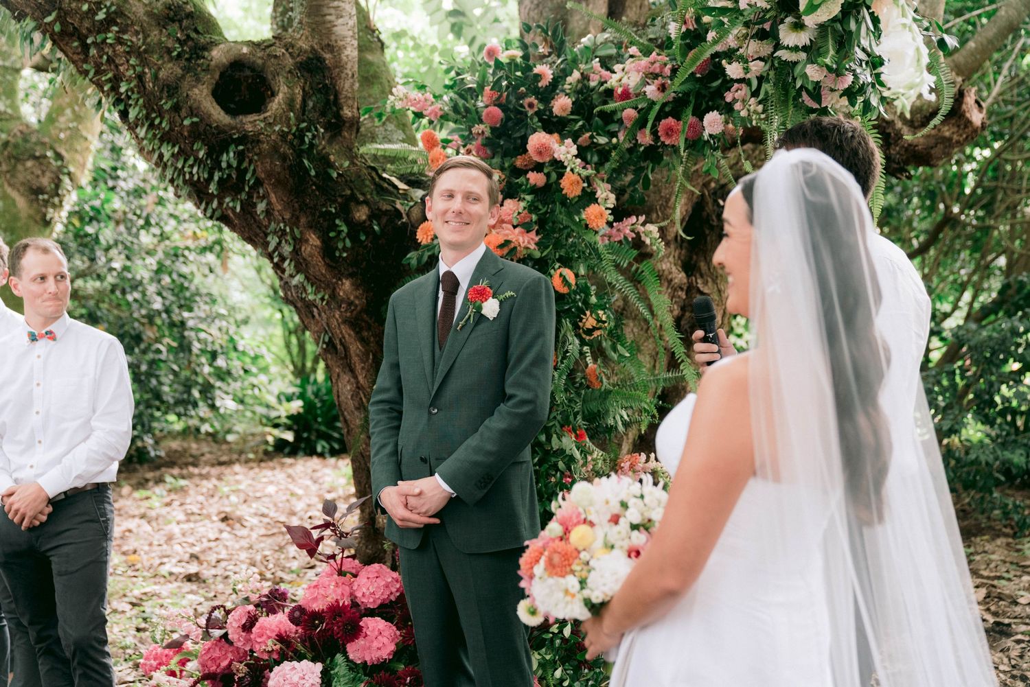 Outdoor wedding ceremony under a blooming tree with pink flowers.