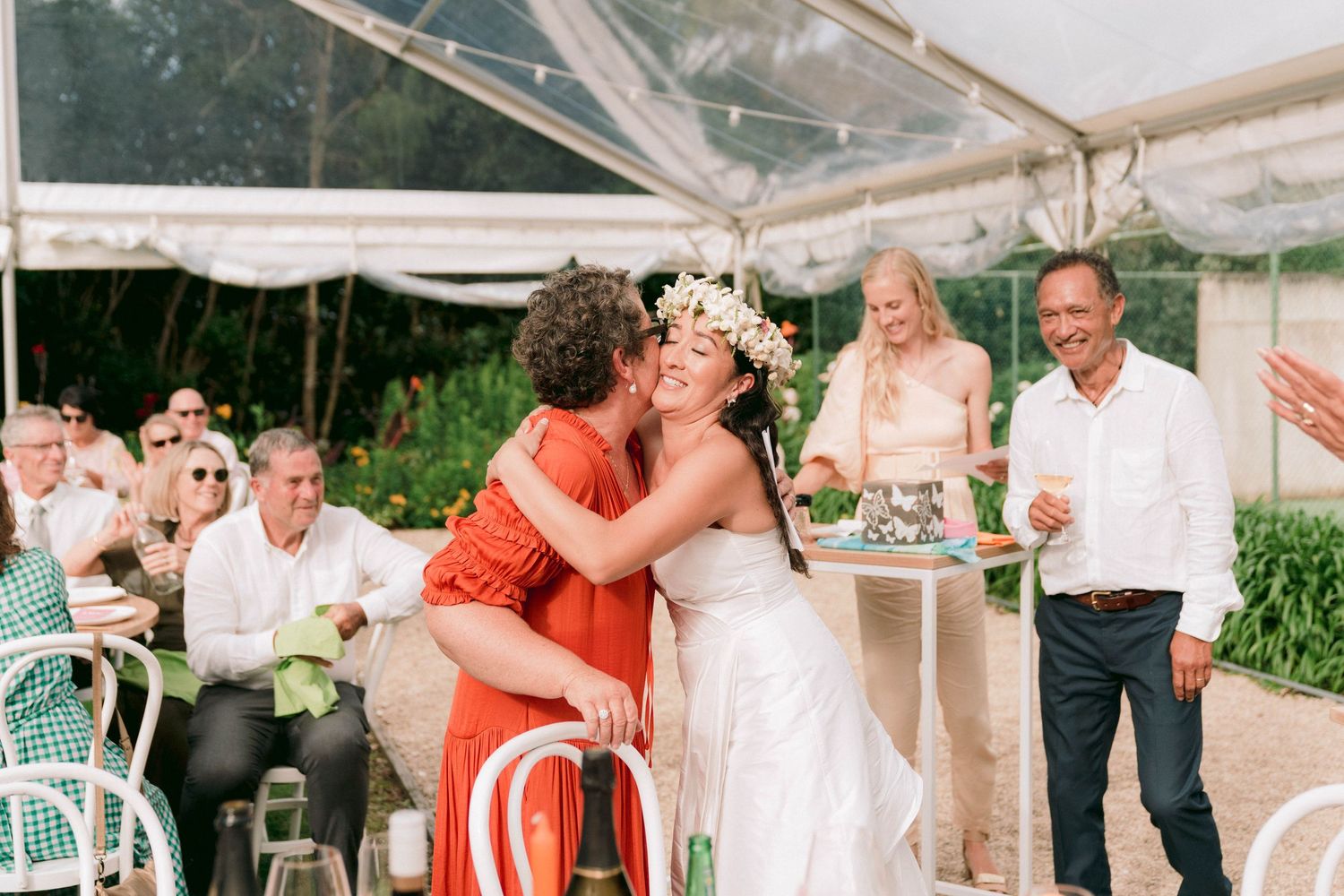 Wedding celebration under a white tent with guests watching a special moment.