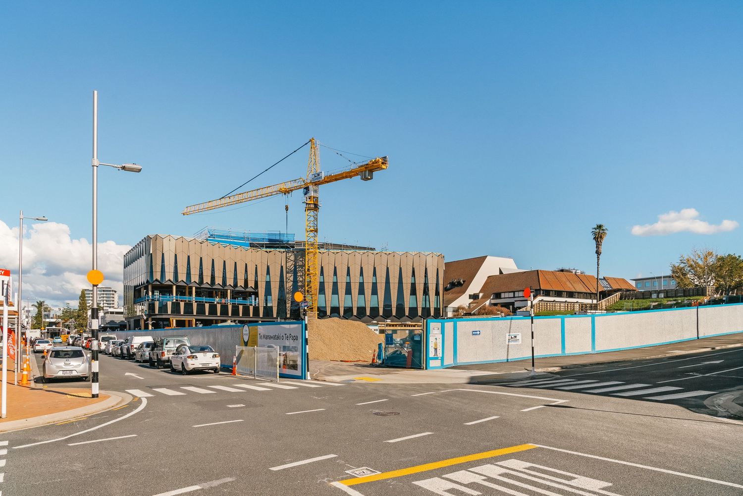 Wide angle panoramic view of an empty parking lot with construction cranes in the background.