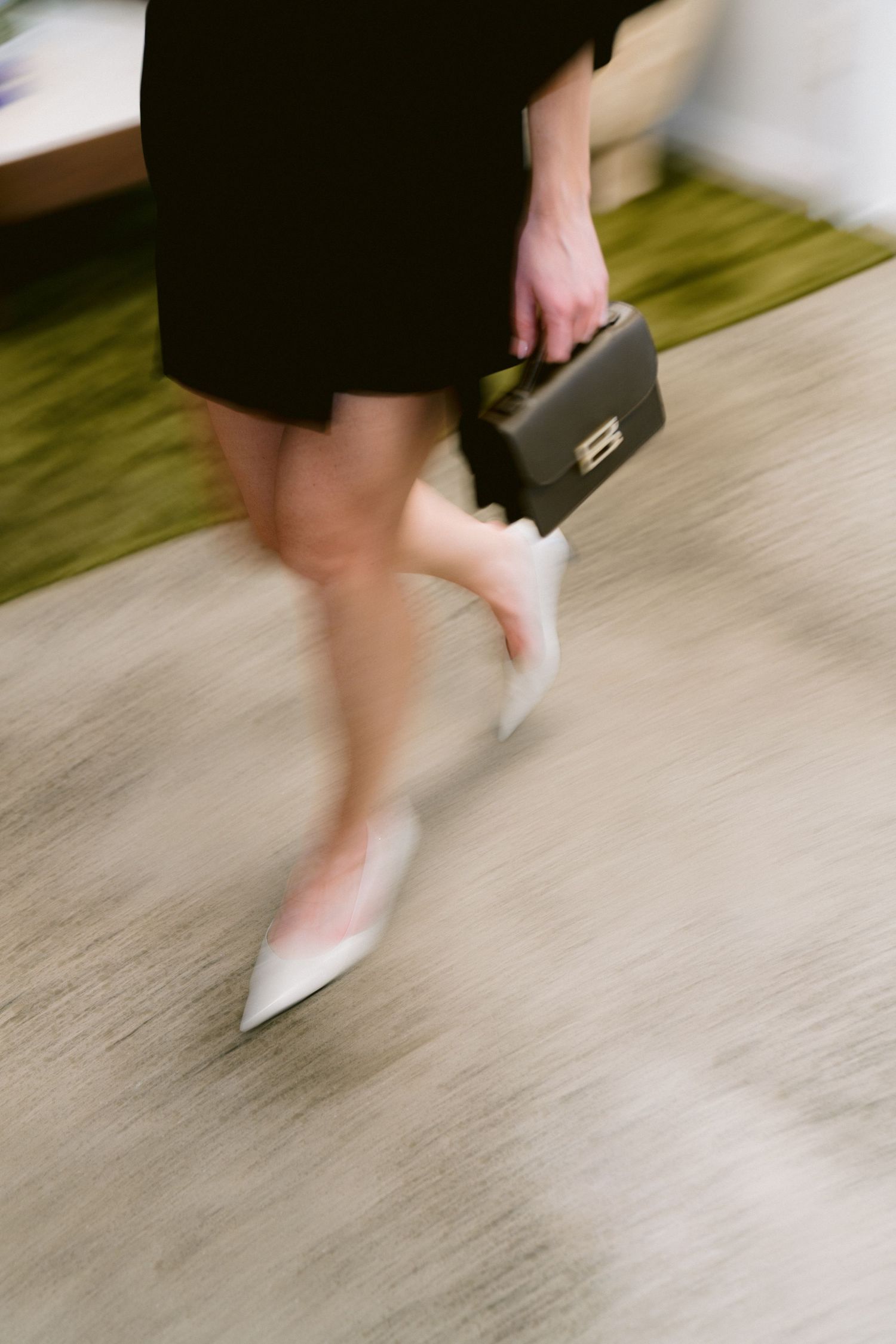 Motion-blurred sequence showing walking feet in white shoes against a light floor, creating a sense of movement.