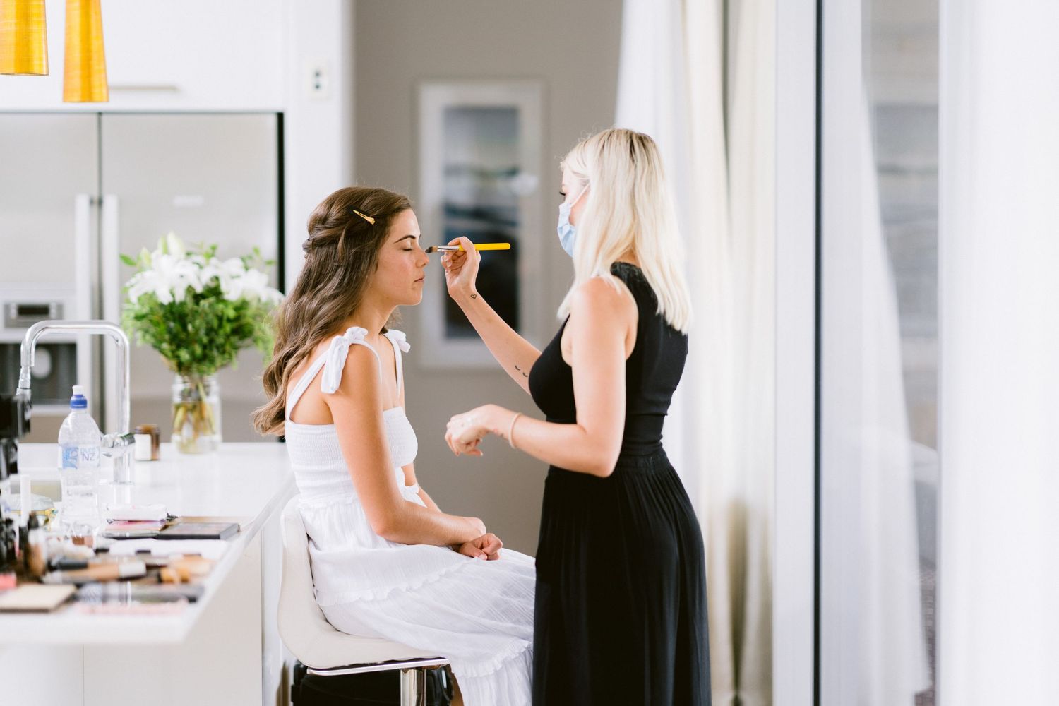 Two women cooking together in modern white kitchen while talking and preparing food.