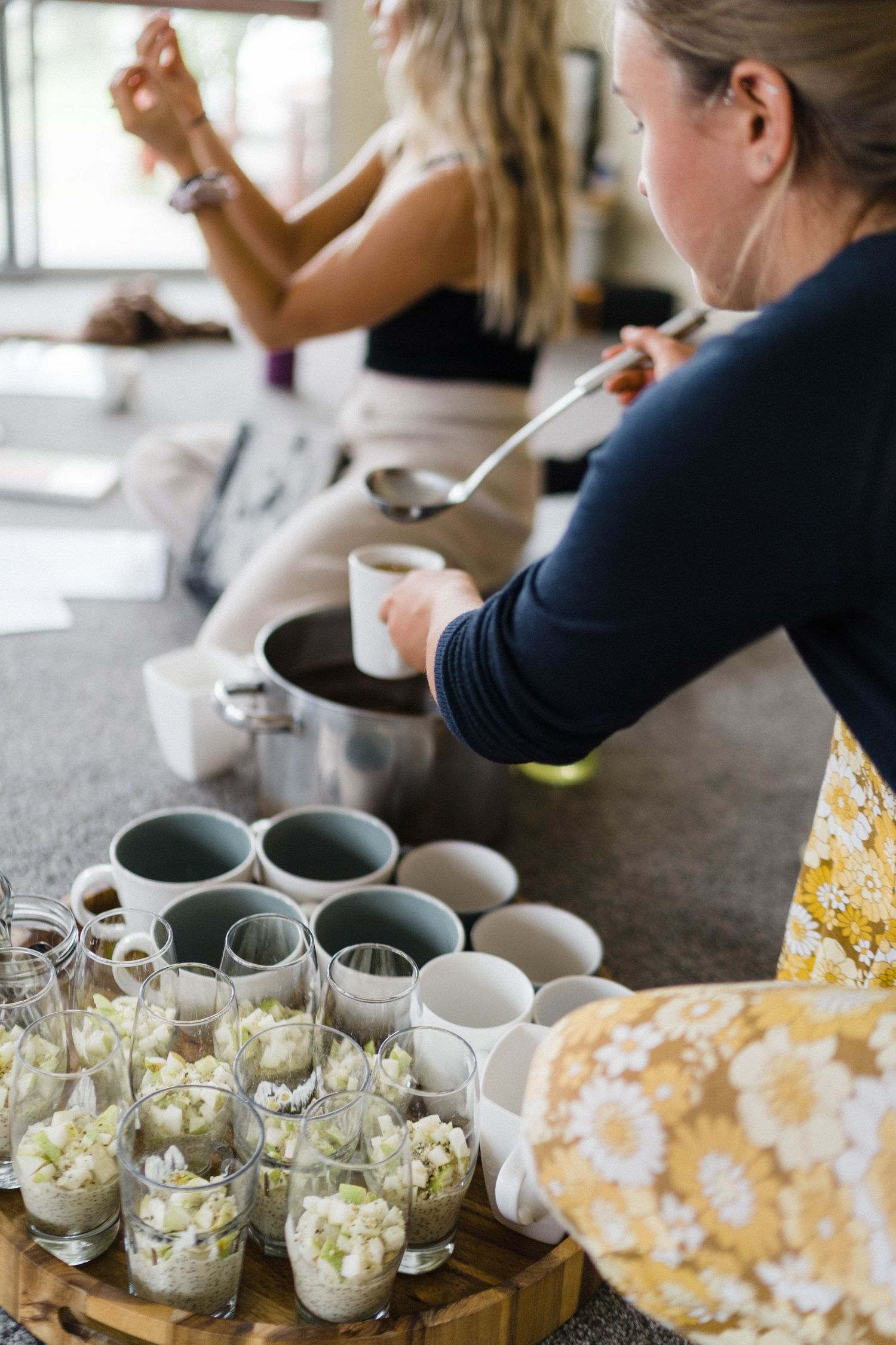 Various drinks and snacks being prepared on wooden serving board at wellness gathering.