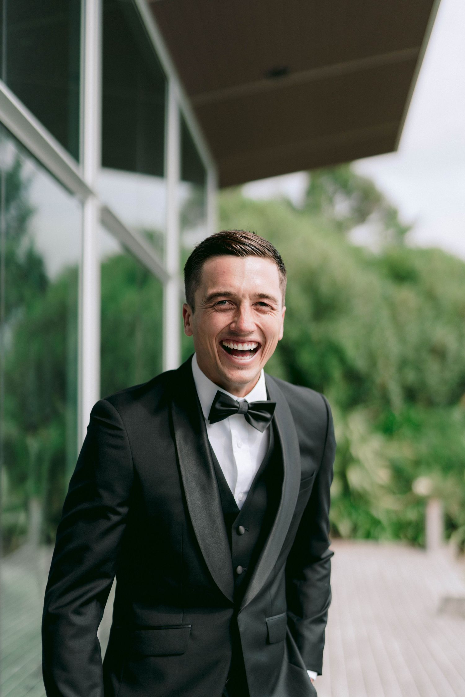 A person in a black tuxedo and bow tie smiling during a formal event.