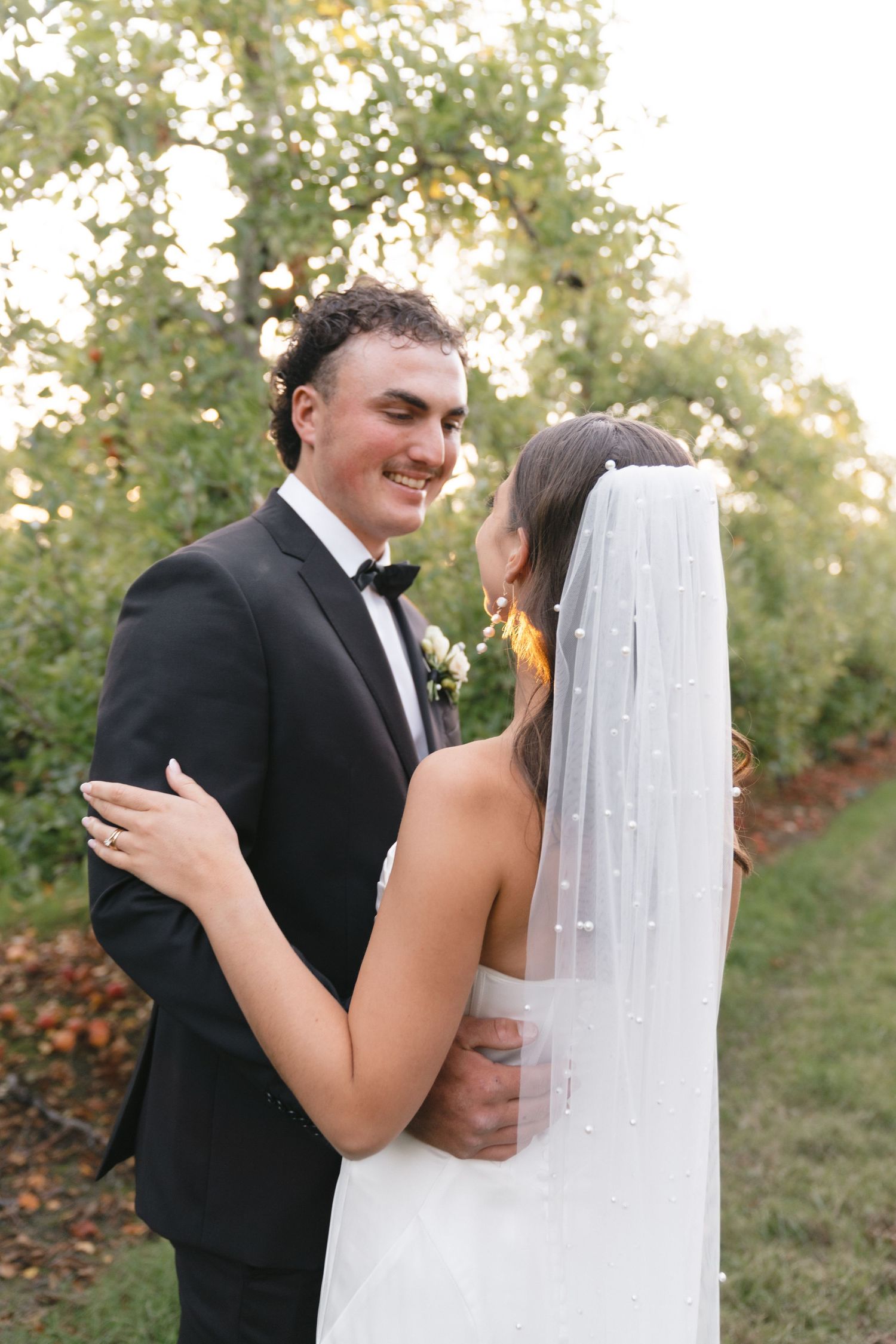 A tender wedding moment captured in an outdoor garden setting during golden hour.