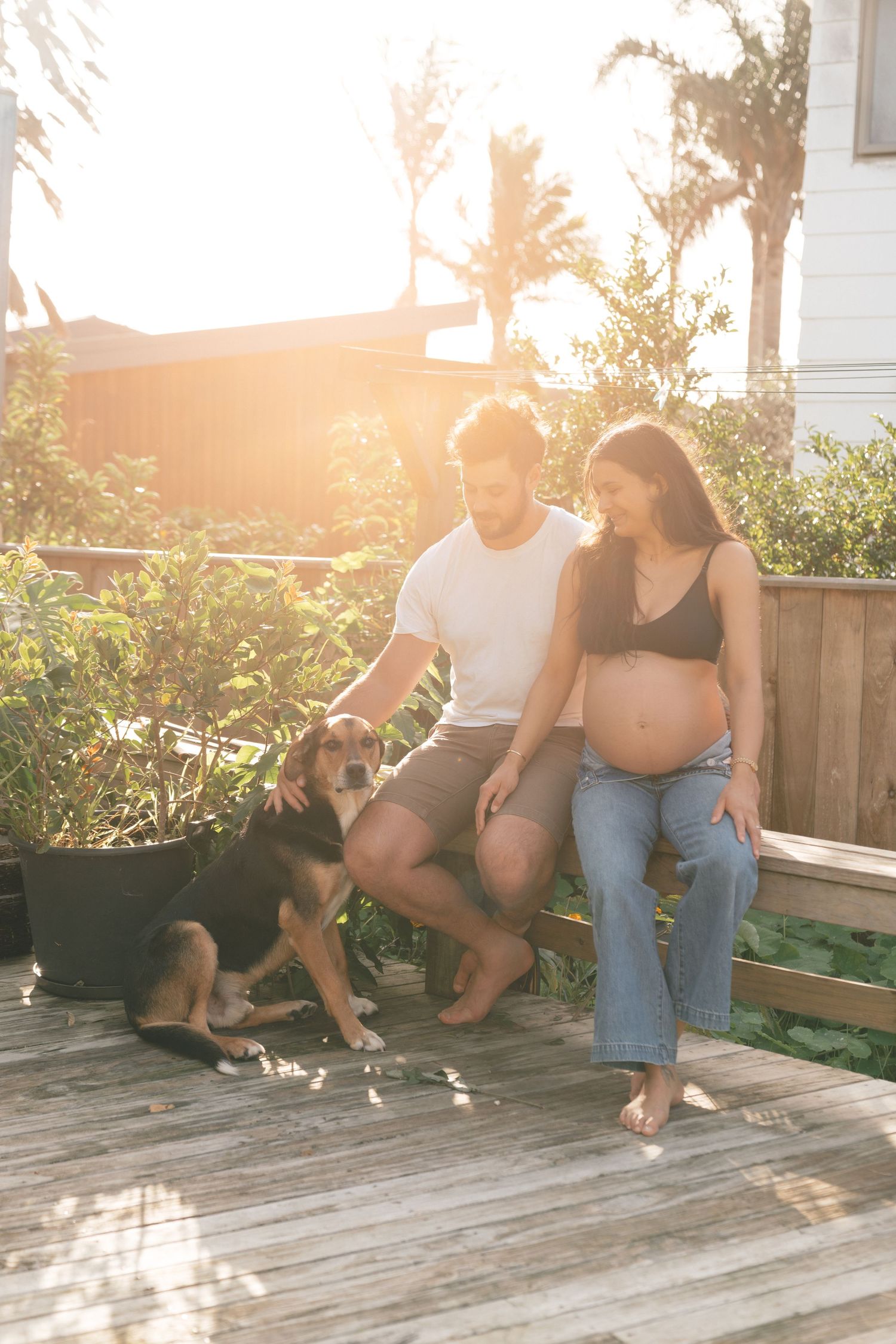 A couple and their dog enjoy a sunset moment together on their backyard deck.