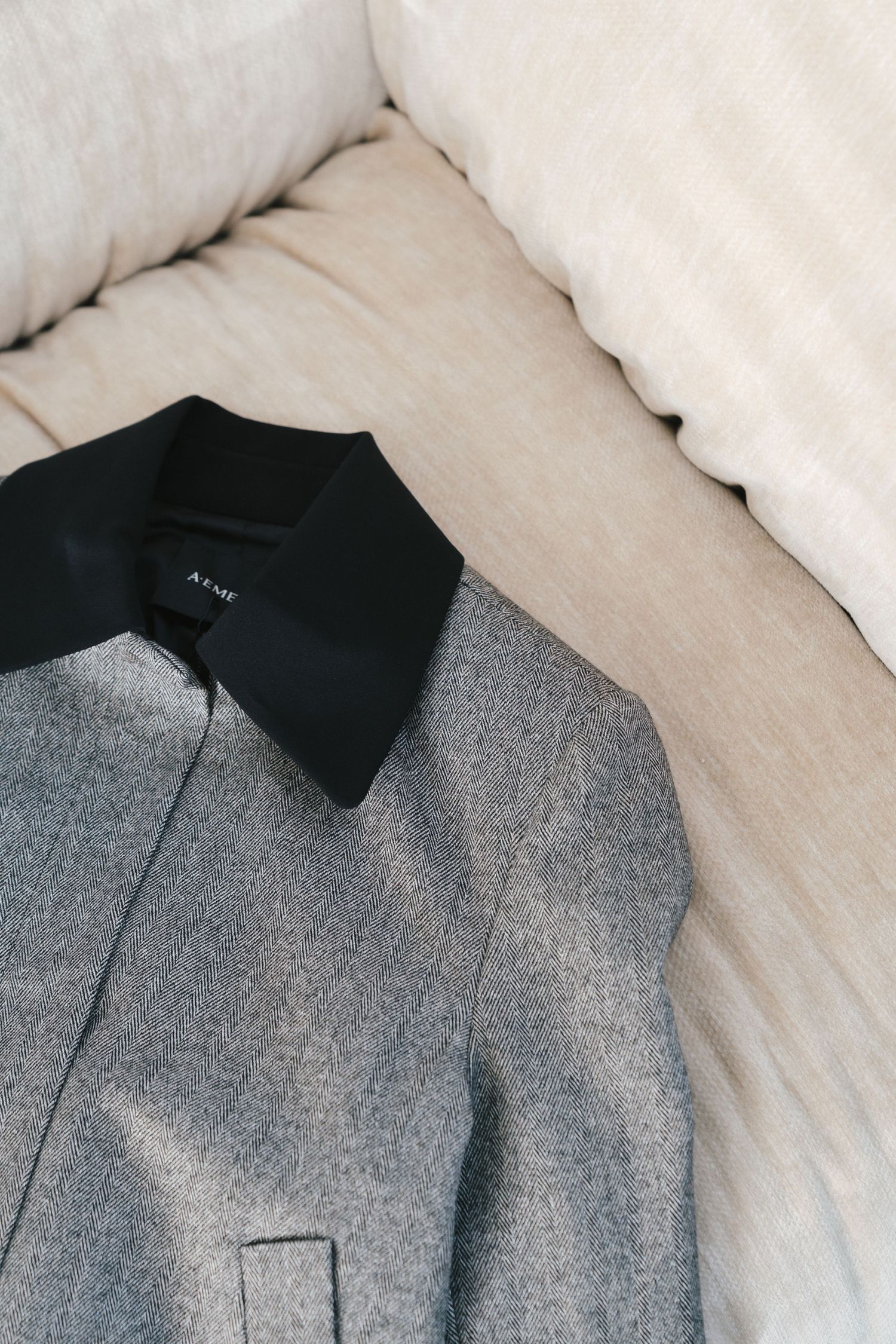 Close-up detail of a grey wool coat with black contrasting collar showing tailored construction and fabric texture.