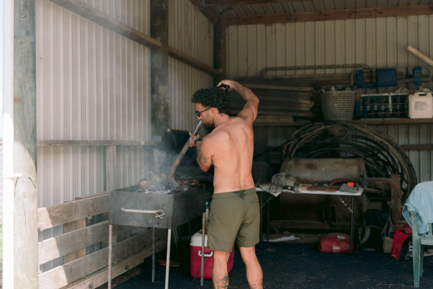 Person cooking on a barbecue grill inside a workshop or garage space.