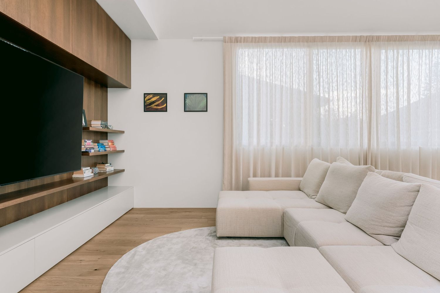 Minimalist living room with wooden accent wall, white sectional sofa and entertainment unit.