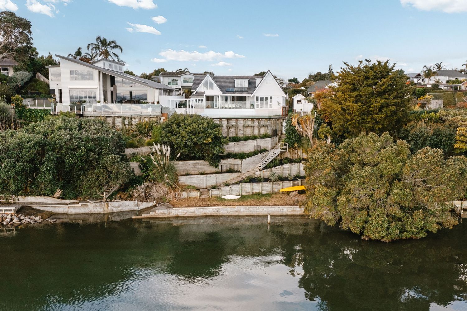 Coastal homes perched on rocky cliffs overlooking a serene waterfront.
