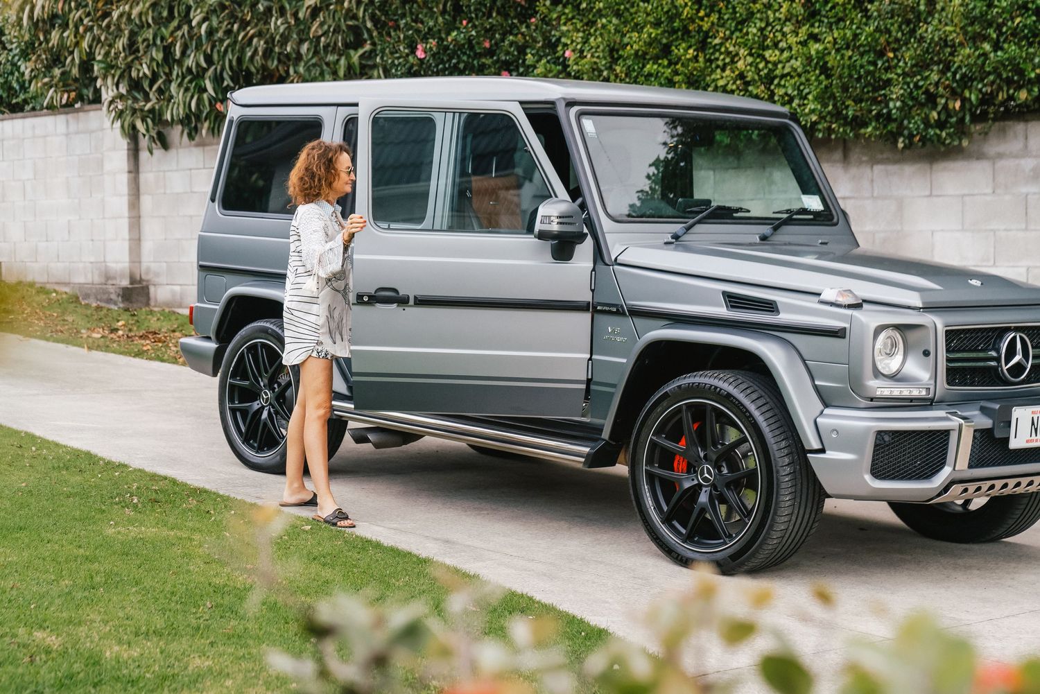 Luxury silver Mercedes G-Wagon parked outside modern residential property.