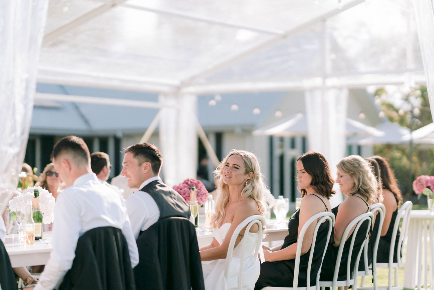 Wedding reception under white tent with elegant table settings and decor.