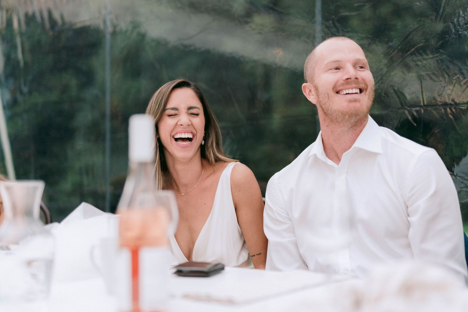 Happy guests share laughter during an outdoor wedding celebration.