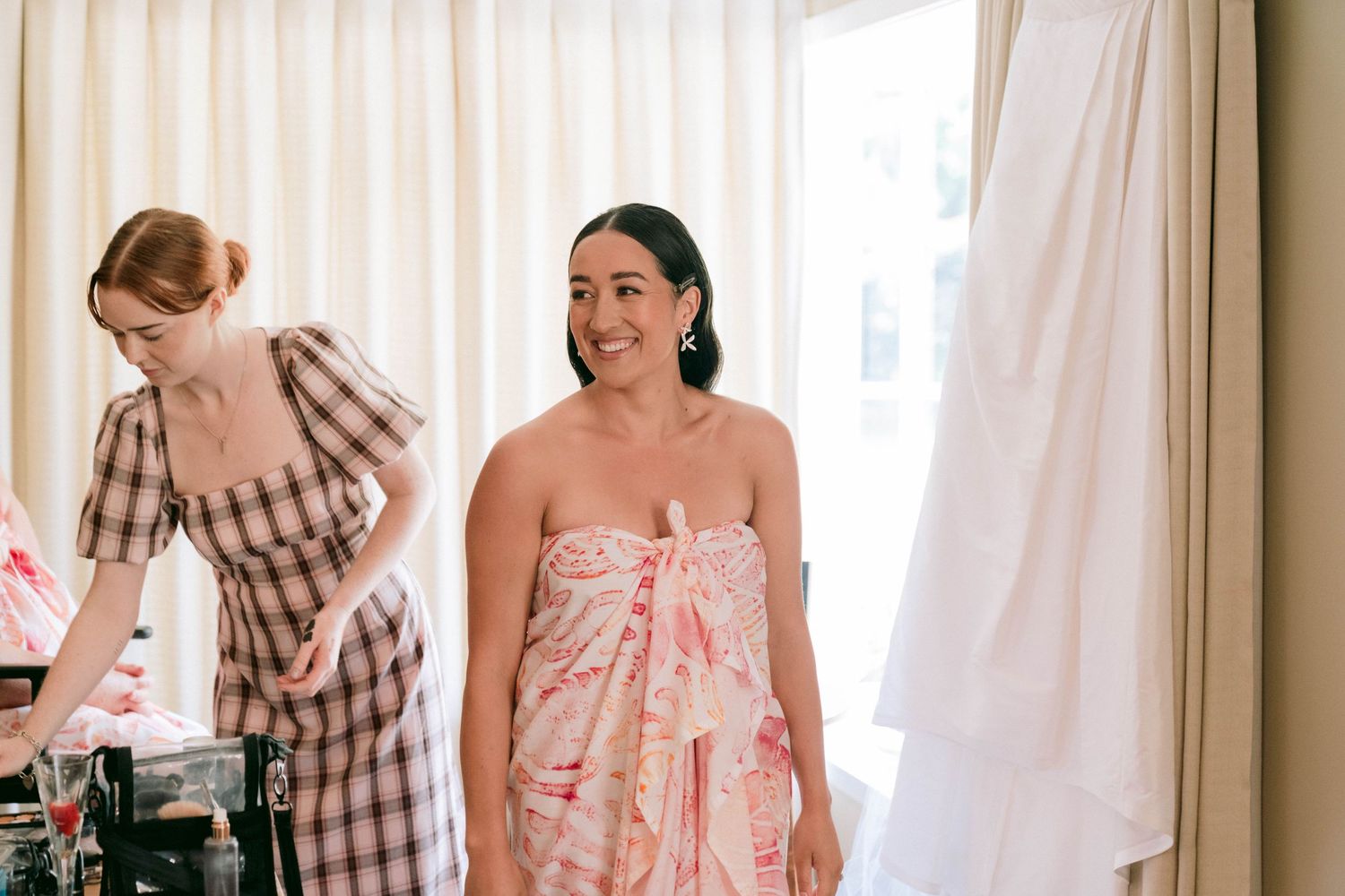 Bridal preparations in a sun-lit room with flowing curtains.