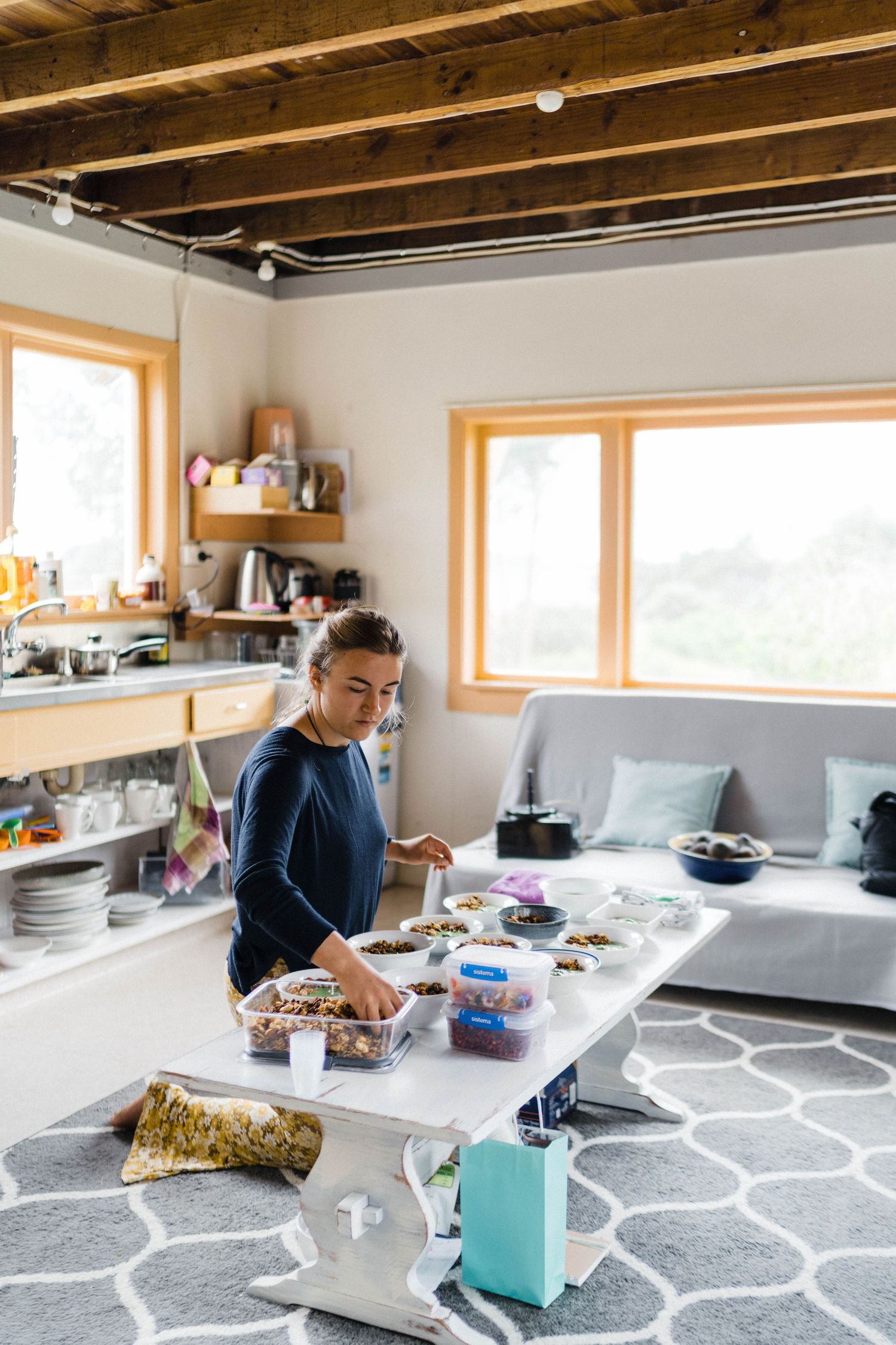Preparing food at a rustic kitchen counter with wooden ceiling beams and large windows.