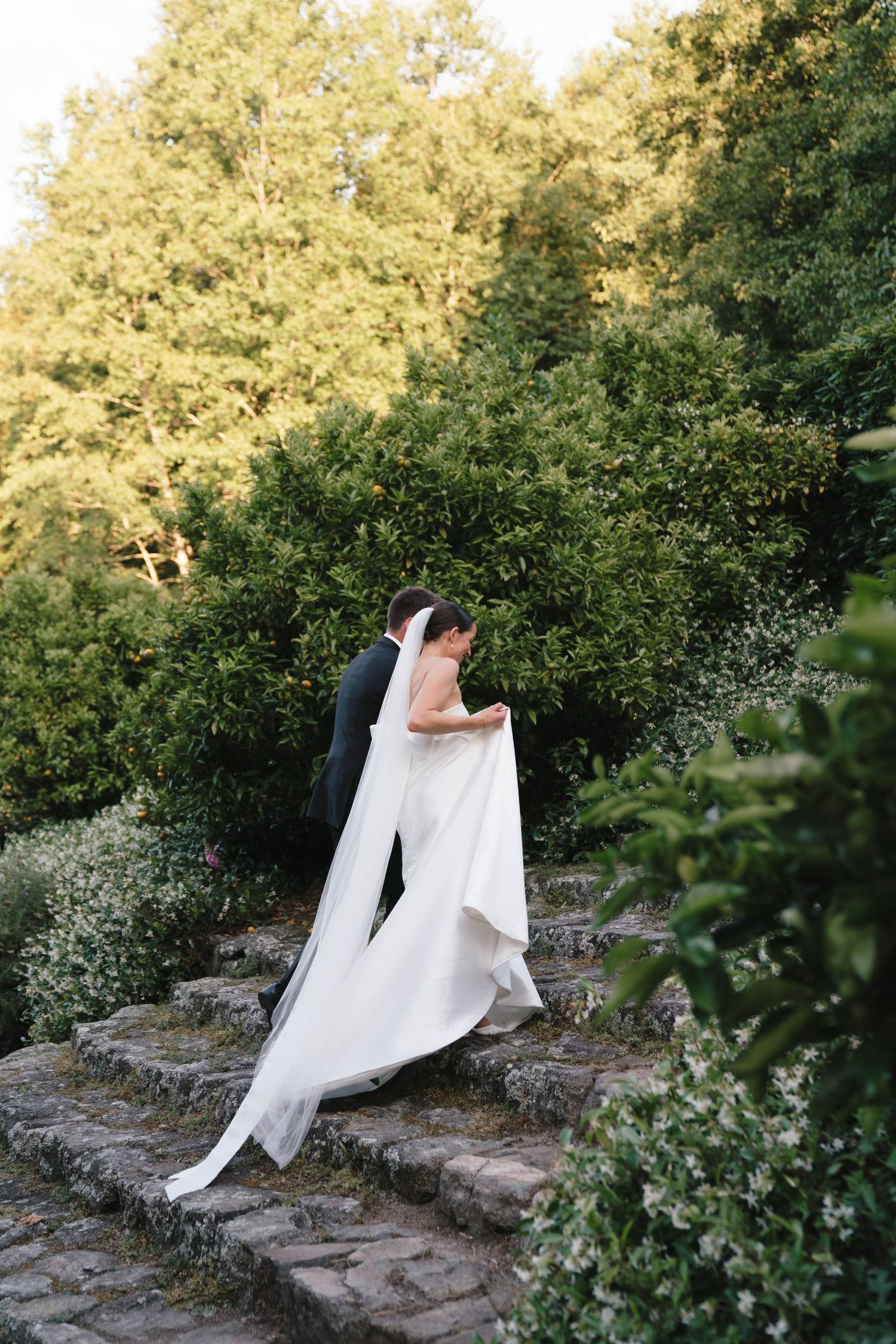 Wedding couple embracing on stone steps with flowing white dress.