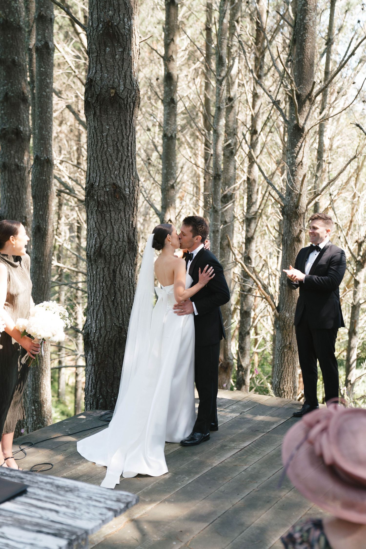 A couple shares their first kiss during an intimate forest wedding ceremony.