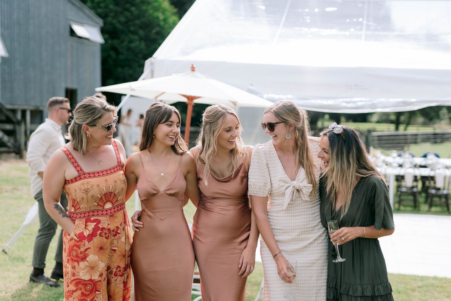 Wedding guests in coordinated outfits standing together under a white tent.