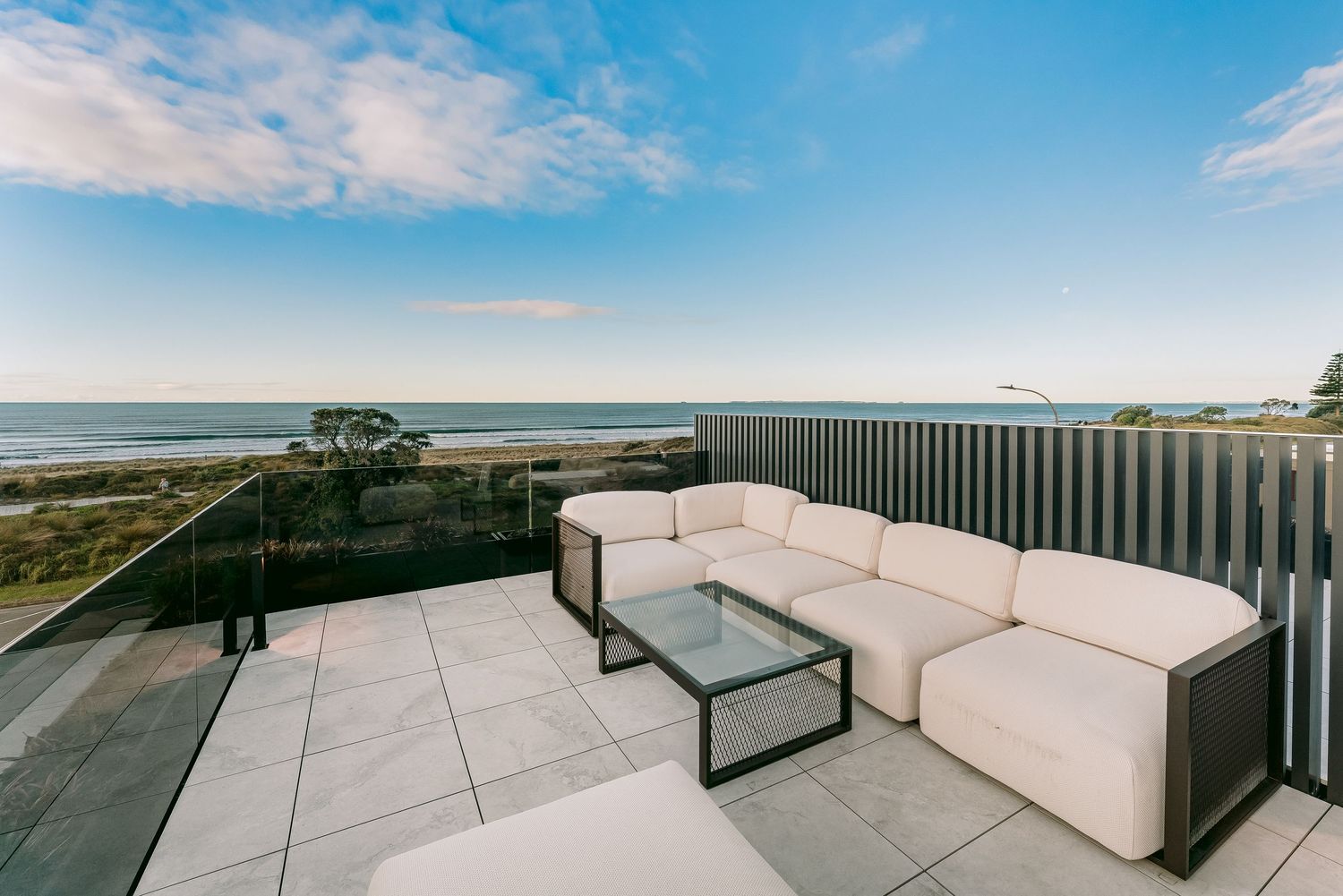 Luxurious rooftop terrace with white sectional sofa offering panoramic ocean views.