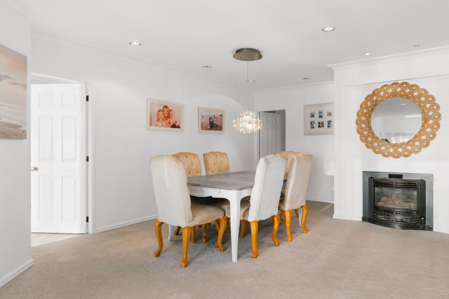Modern white dining room with gold accent mirror and elegant table setting in open concept space.