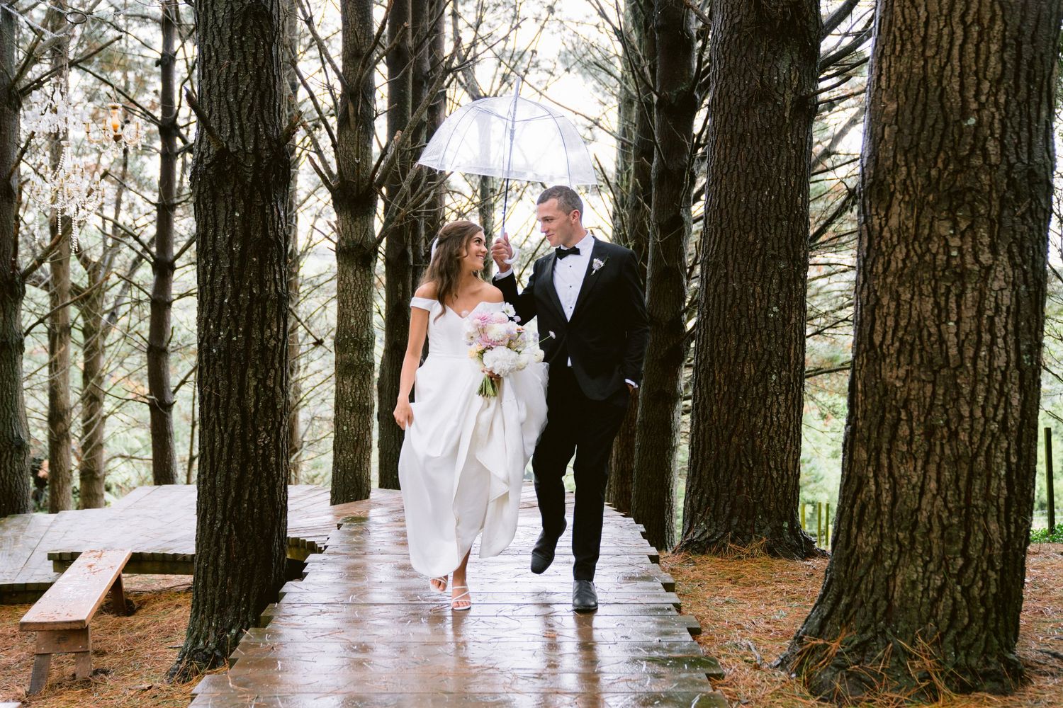 A wedding photo shoot among tall pine trees in a forest setting.