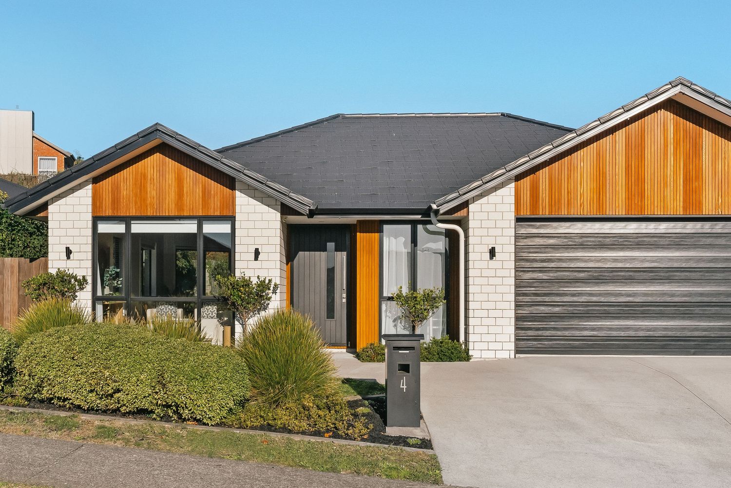 Contemporary house facade with white brick, timber features, and double garage doors.