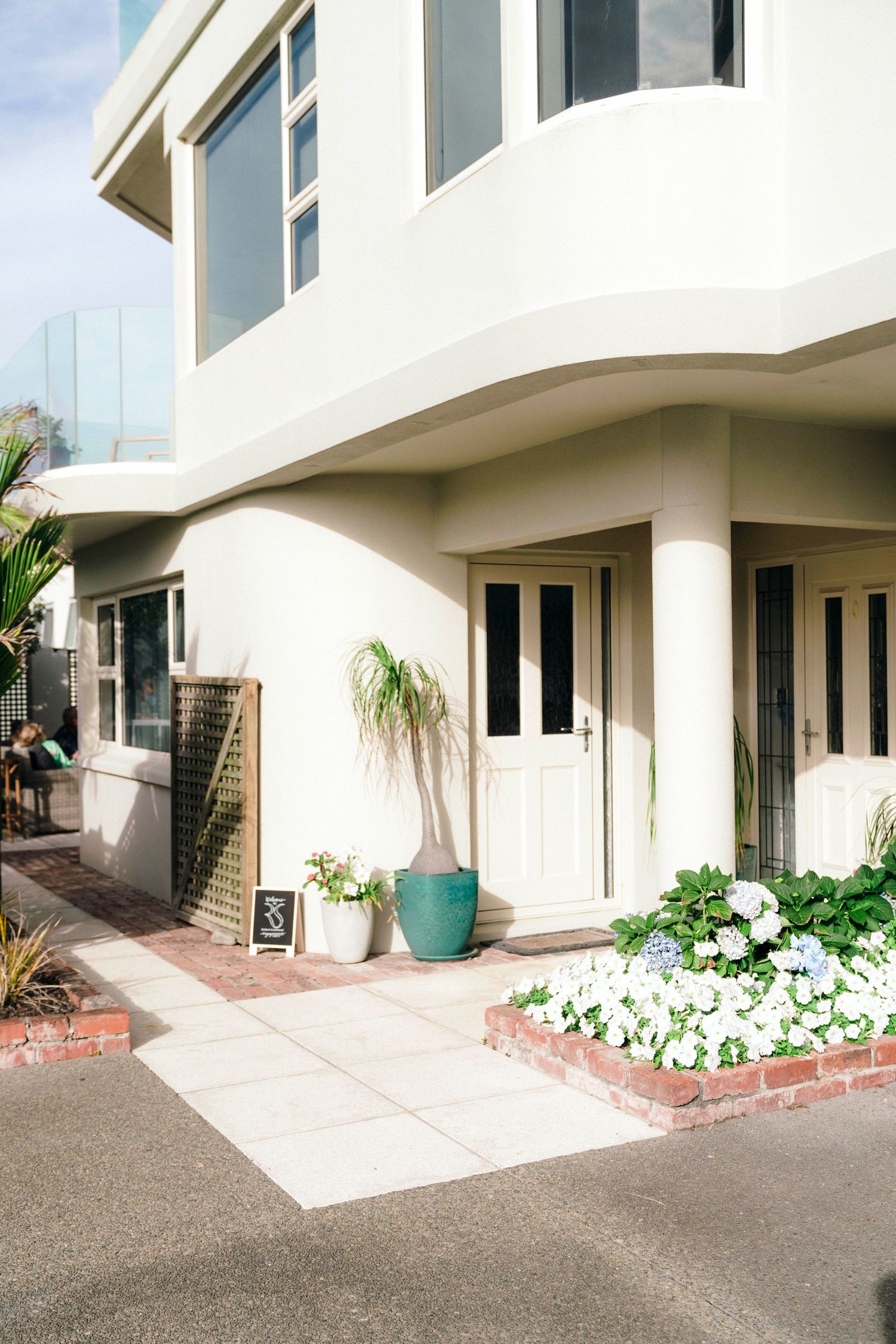 Modern white residential exterior with clean lines and landscaped walkway showing multiple connected entryways.