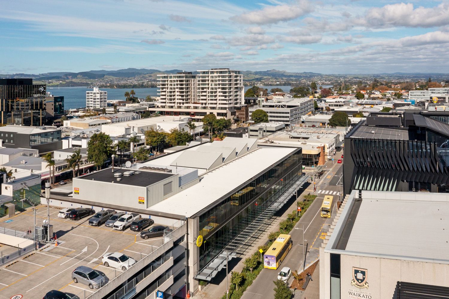 Aerial view of waterfront commercial district with modern buildings and parking areas.