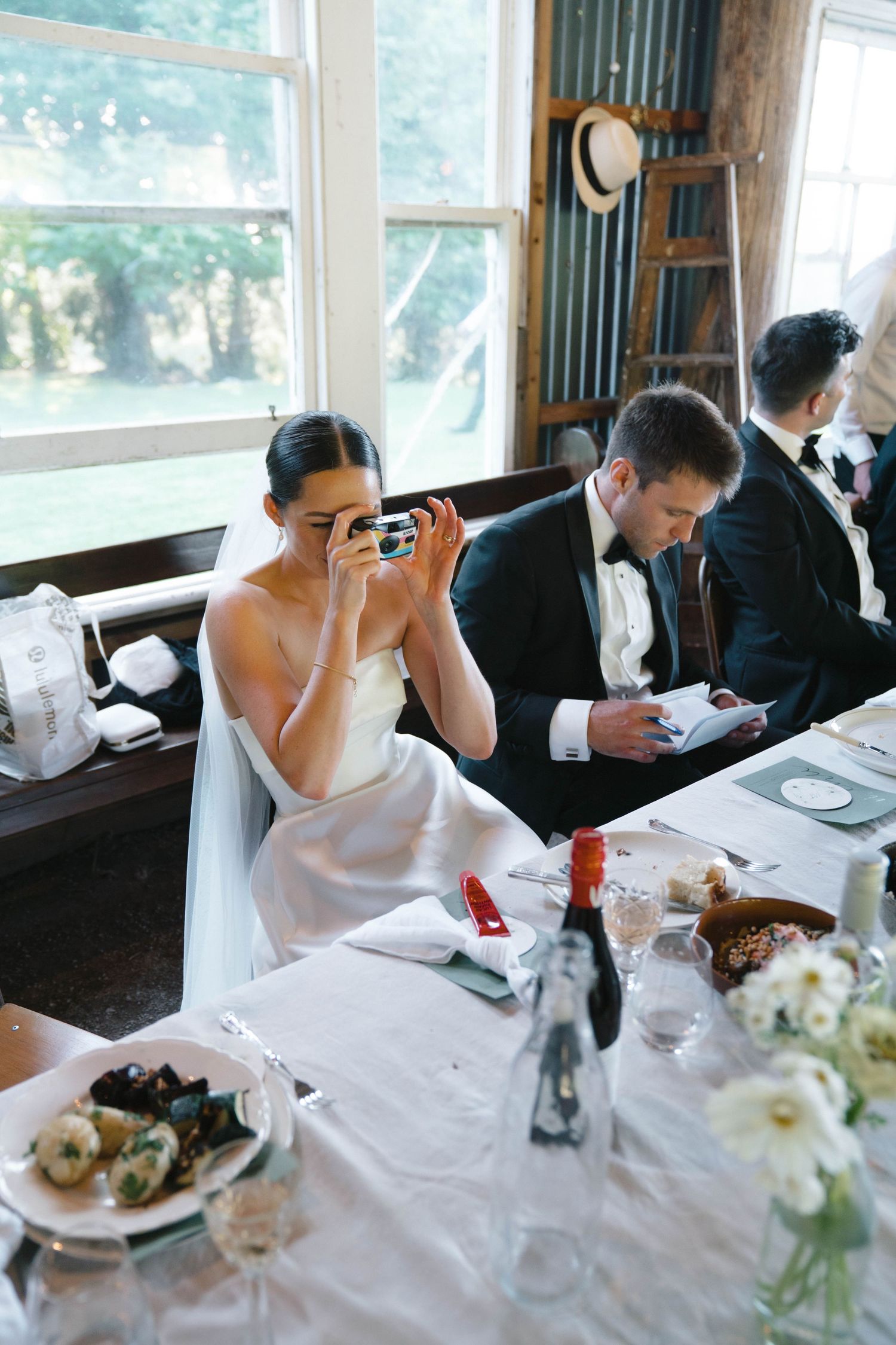 Reception dining scene showing place settings and formal table arrangements in a bright windowed room.