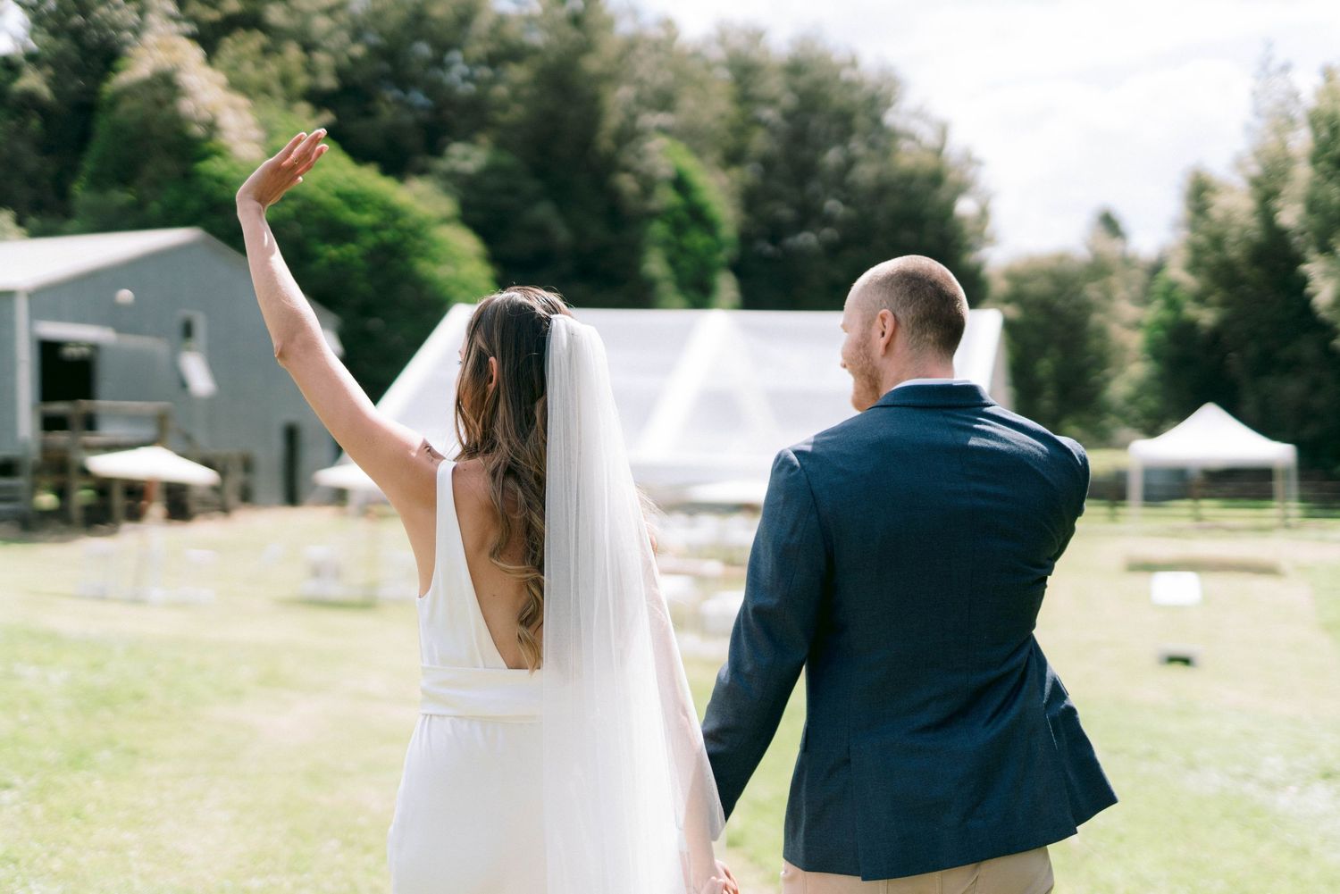 Newlyweds walking hand in hand celebrate with raised arms on their wedding day.
