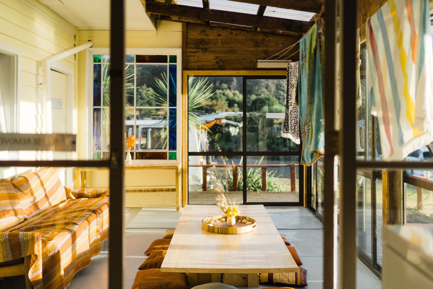 Modern wooden dining room interior with large windows and natural light streaming through the space.
