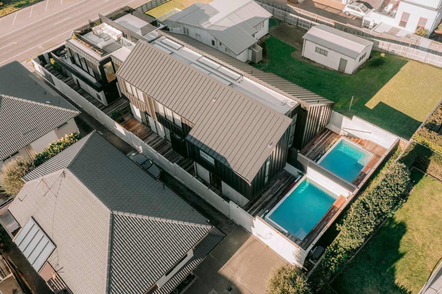 Aerial view of a modern house with two swimming pools and landscaped gardens.