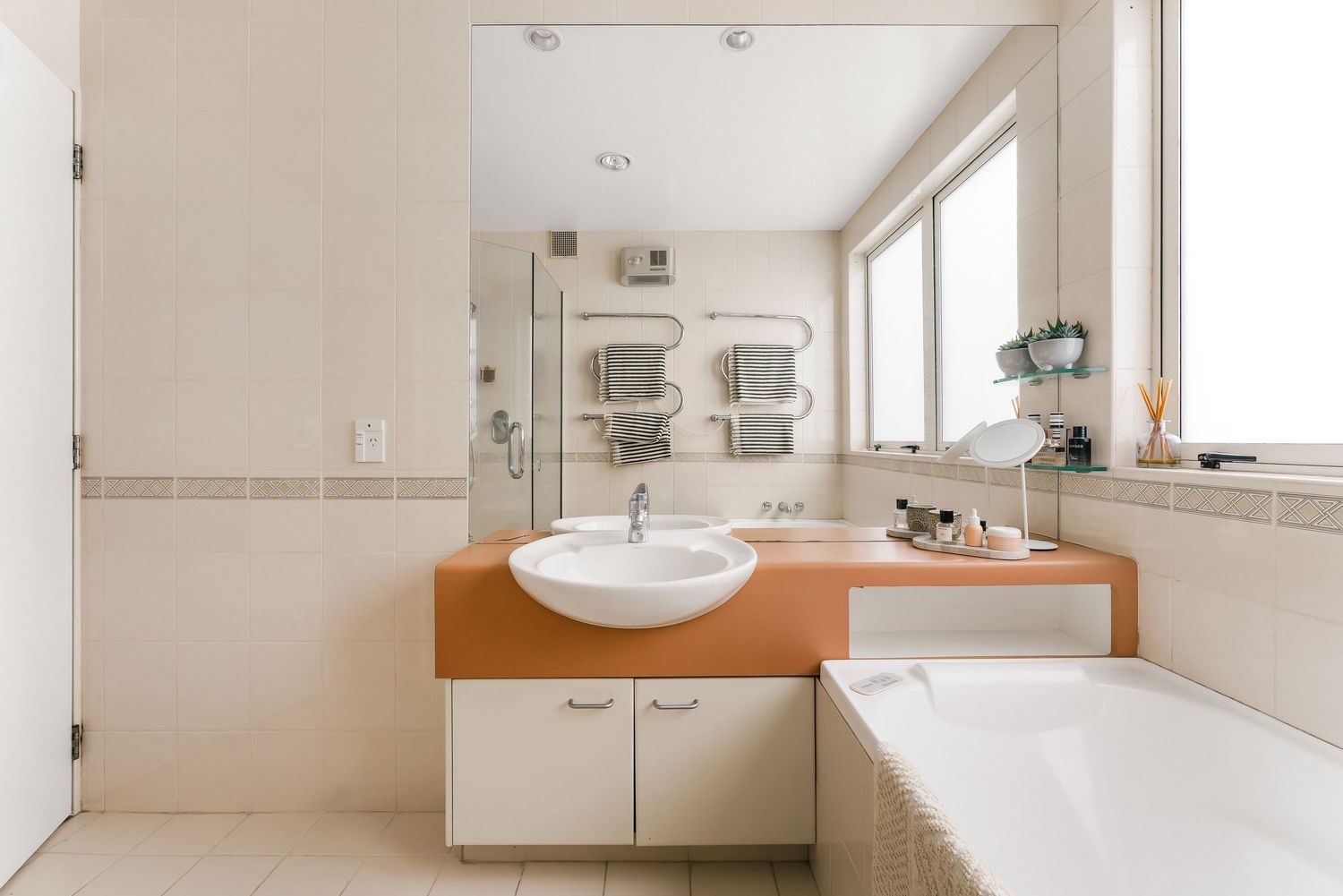 Modern bathroom with white vanity, wooden countertop and large mirror above sink.