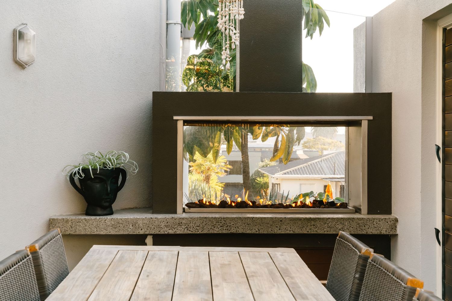 Modern outdoor terrace with wood decking and built-in seating overlooking palm trees.