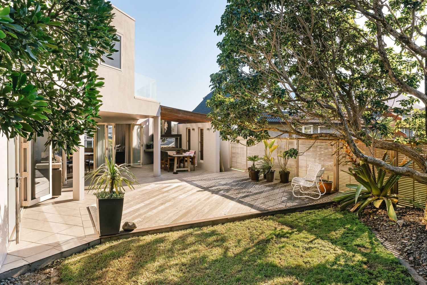 Landscaped garden area surrounding modern white residential building with trees and greenery.