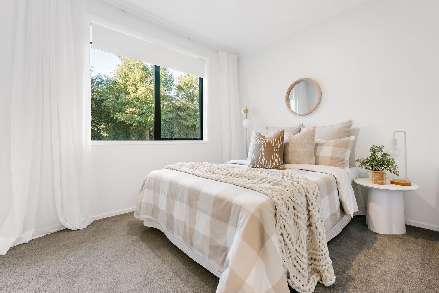 Bright and modern bedroom interior with white bedding, natural light, and decorative accents.