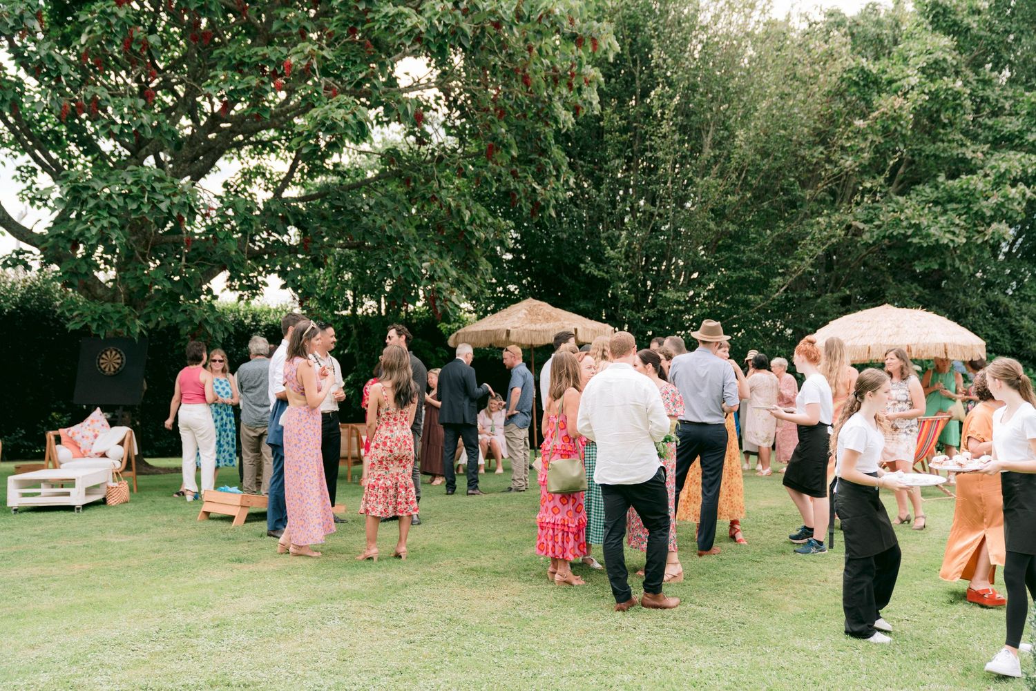 Wedding guests mingling on a lawn during an outdoor reception.