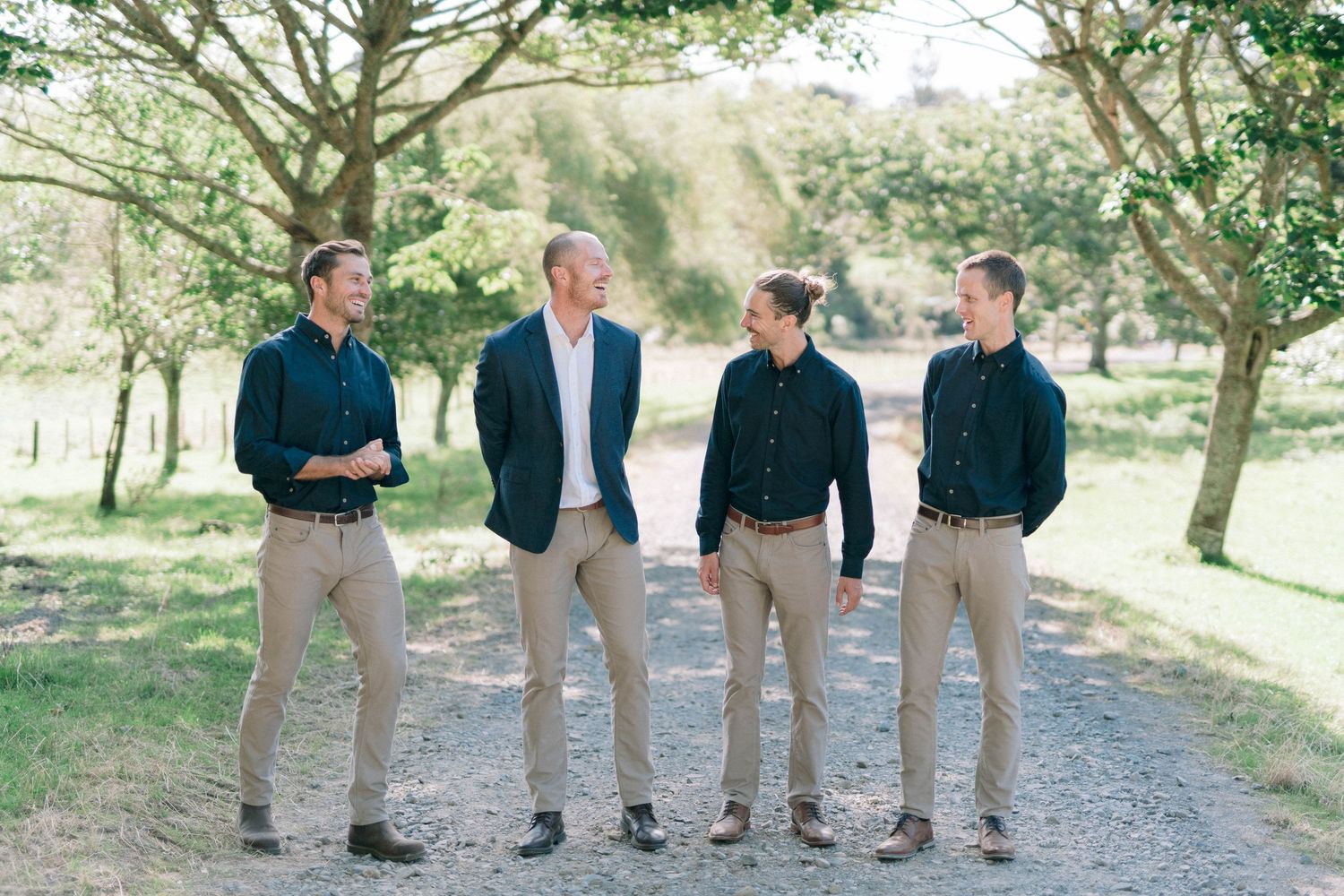 Group of people standing together on outdoor path surrounded by green trees.