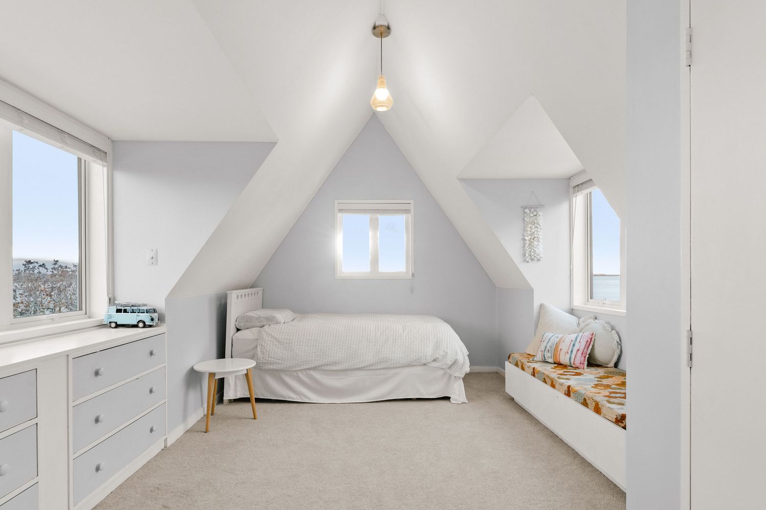 Bright attic bedroom with sloped ceilings and white decor.