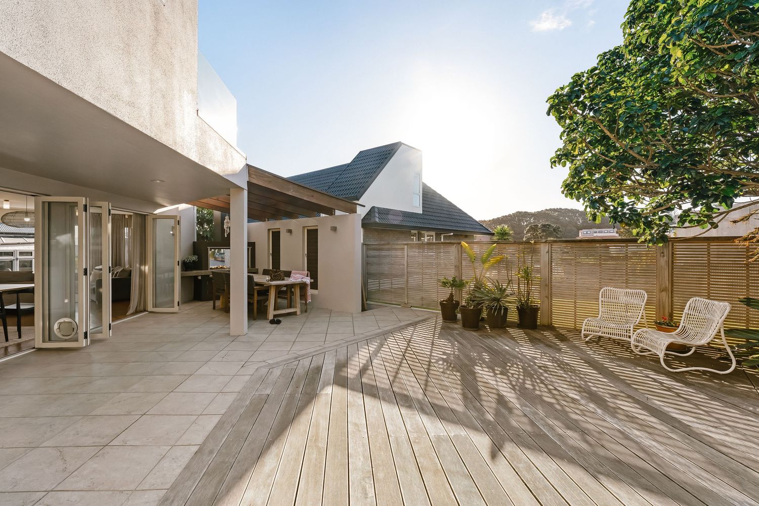 Spacious outdoor deck with wooden flooring, modern furniture, and overhead shade structure.