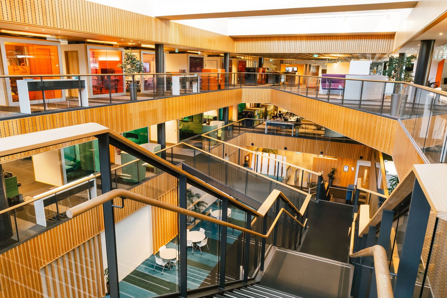 Modern shopping mall interior with wooden accents featuring multiple levels, escalators and glass railings.