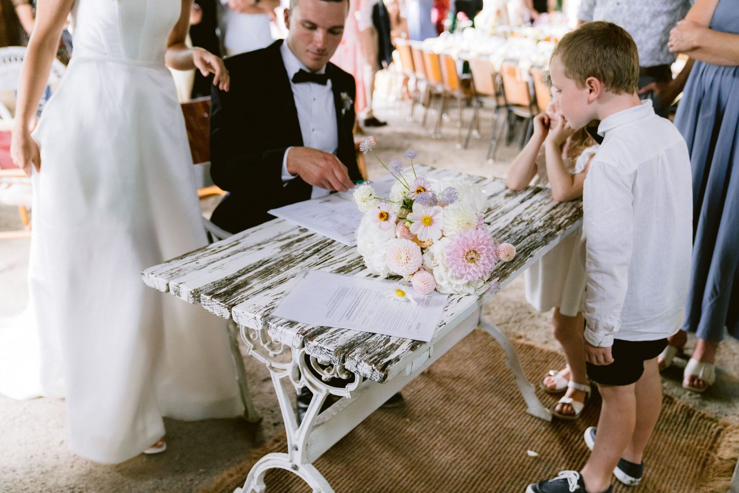 Wedding reception guests mingle and celebrate around decorated tables with pink and white floral centerpieces.