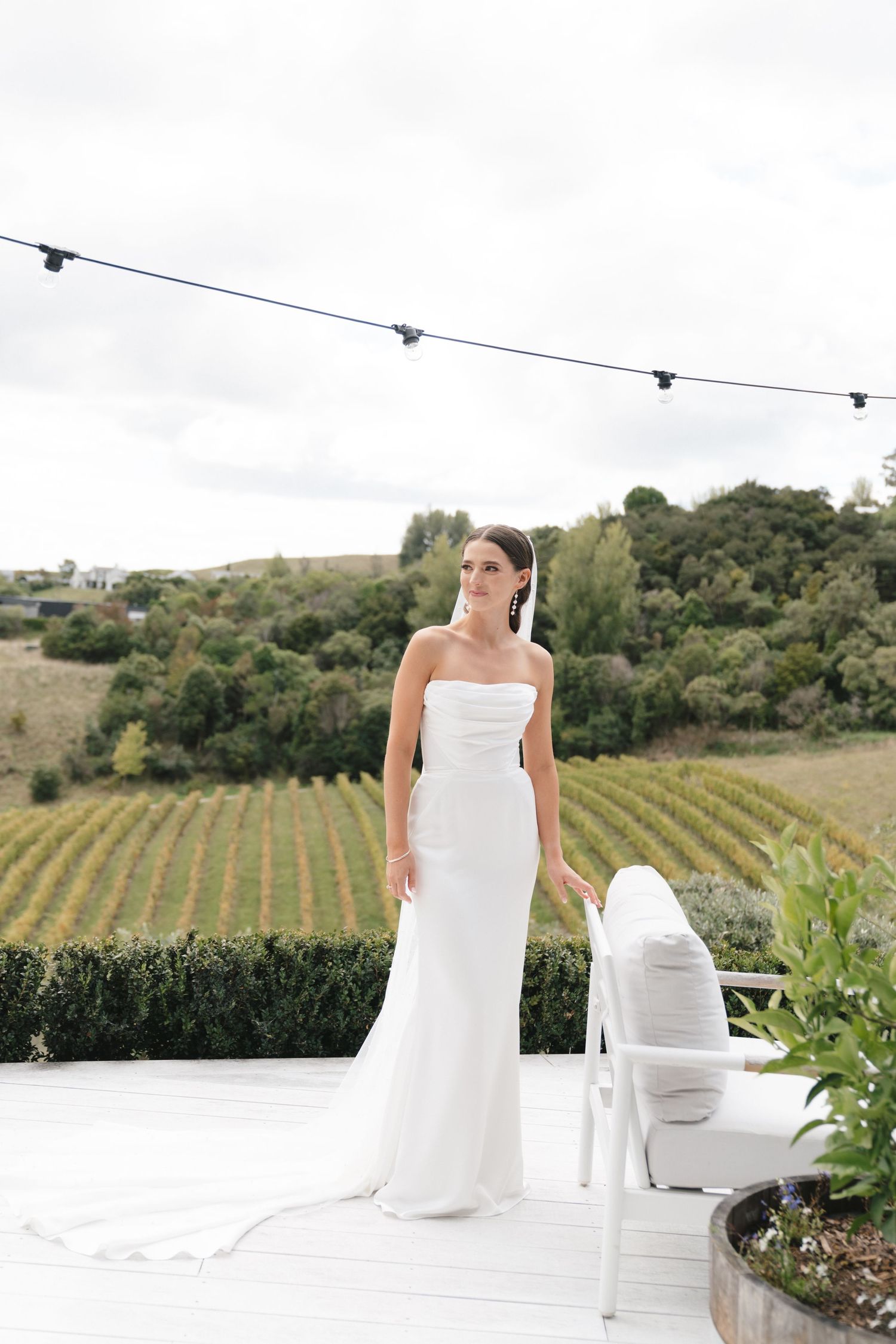 Elegant bridal portrait against vineyard backdrop with flowing white dress.