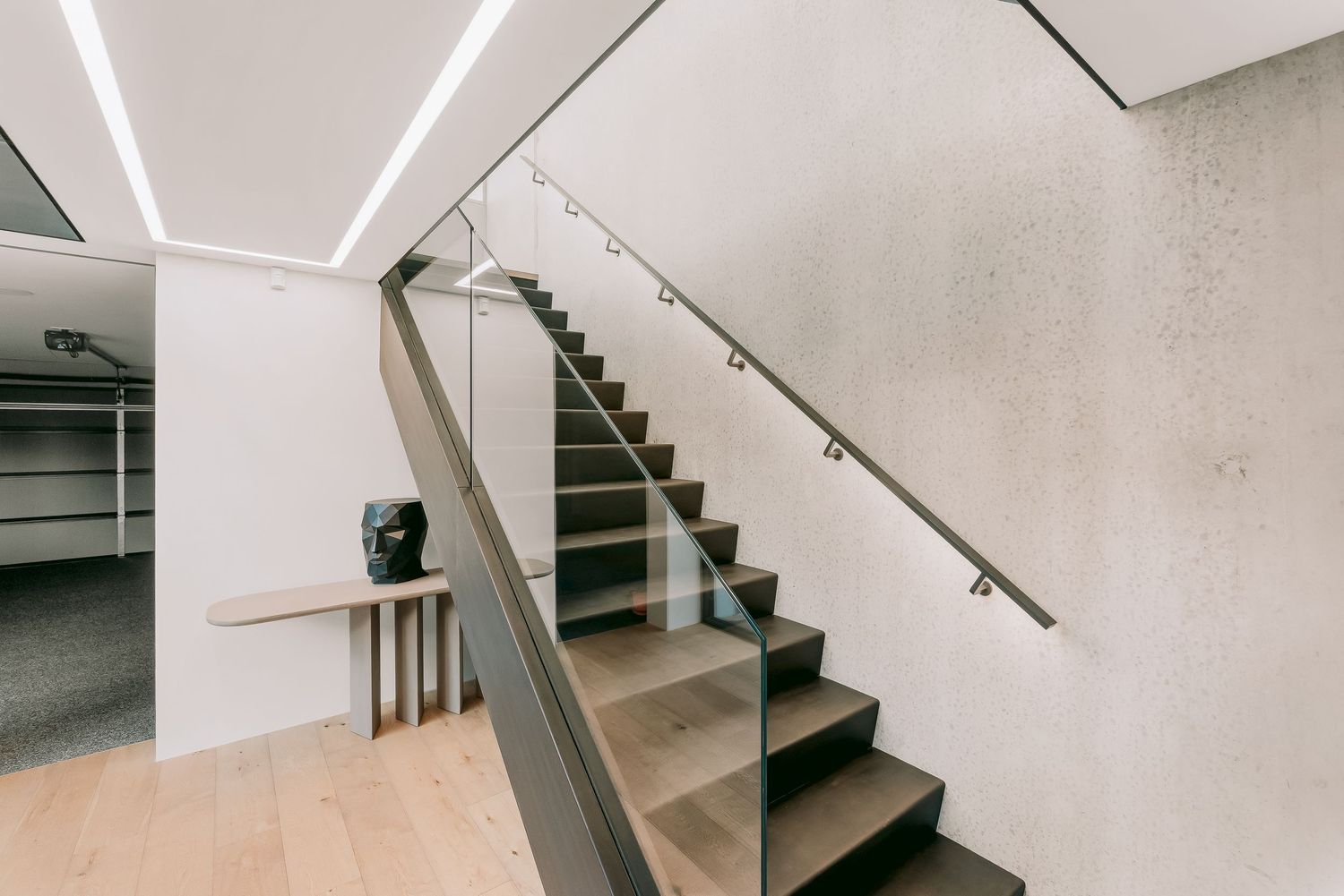 Modern interior staircase with glass railings and sleek lighting design in minimalist style.