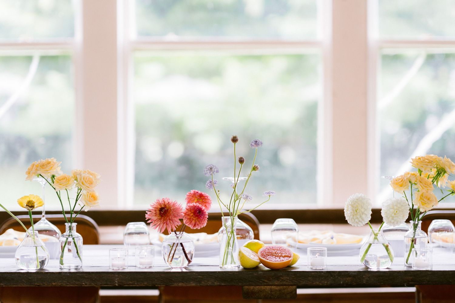 Elegant wedding table settings with delicate floral centerpieces and natural light streaming through windows.