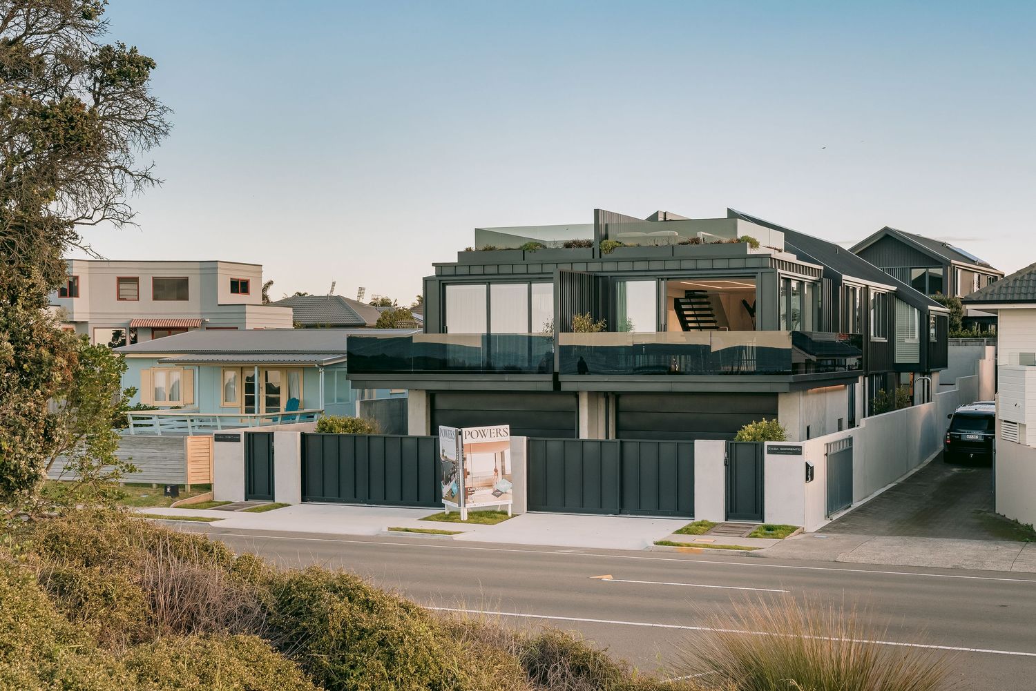 Contemporary multi-level residential buildings with modernist architecture along a suburban street.