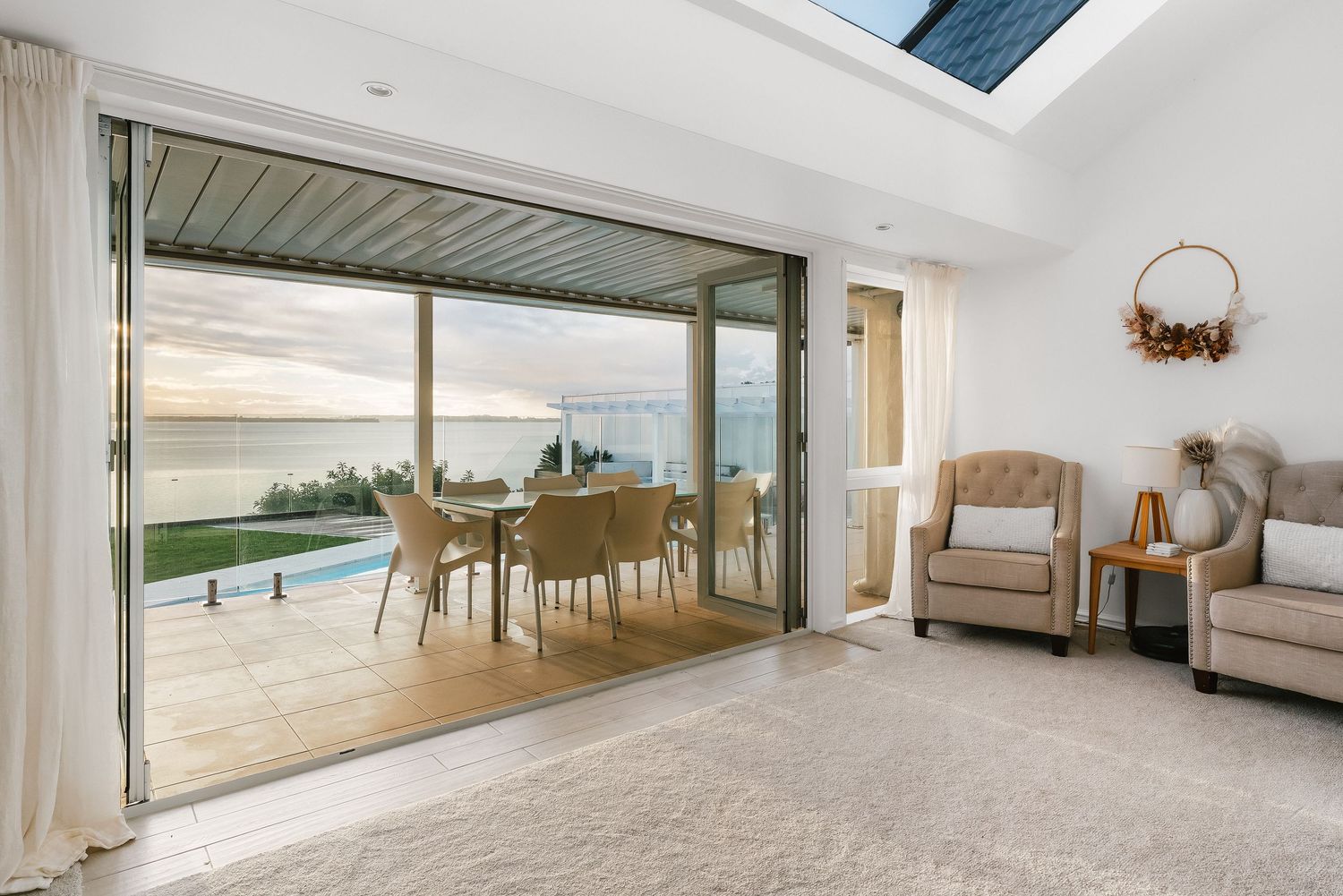 Coastal living room with large sliding doors opening to ocean view and comfortable seating area.