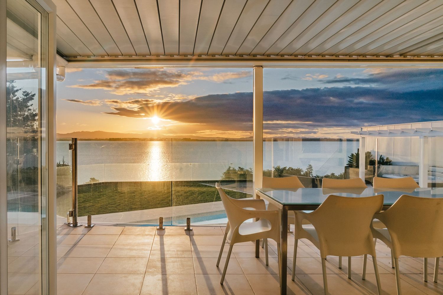Stunning sunset view from covered patio with dining table overlooking the waterfront.