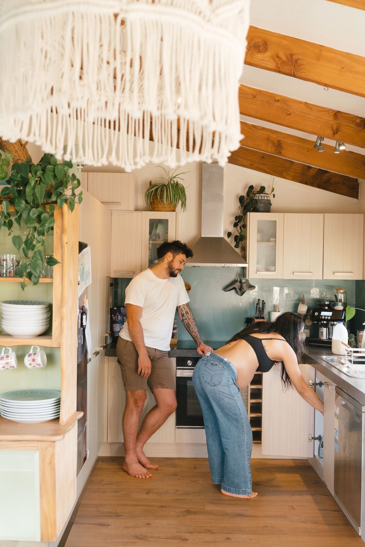 A series of images showing someone organizing and cleaning a bright, modern kitchen with wooden accents and white cabinets.